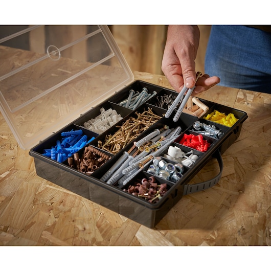 STANLEY 1-92-761 organizer box met diverse schroeven, pluggen en hardware, schuine aanzicht, hand pakt onderdelen.