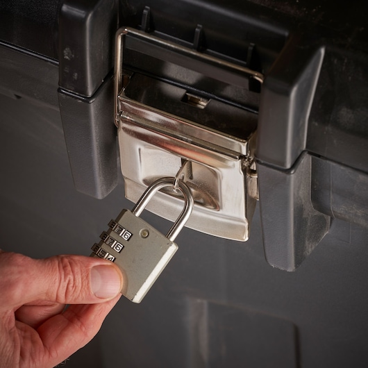 STANLEY 1-92-978 afsluitbare gereedschapskist close-up met combinatieslot op de sluiting en hand die het slot vasthoudt.