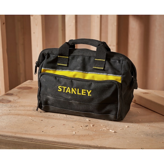 STANLEY 1-93-330 zwarte en gele gereedschapstas met handvatten op een houten werkbank, vooraanzicht.