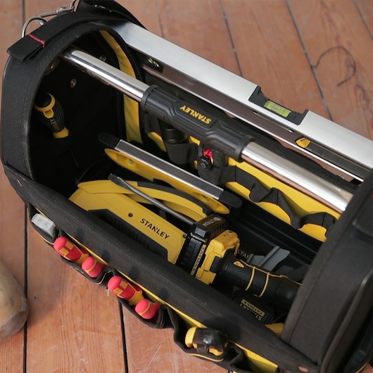 STANLEY 1-93-951 gereedschapstas bovenaanzicht met geel-zwarte handgereedschappen en waterpas op houten vloer.
