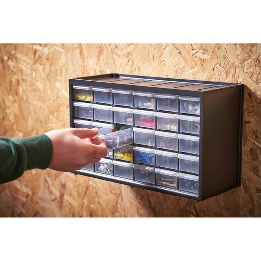 Organisateur STANLEY 1-93-980 avec tiroirs transparents fixé au mur, main accédant au contenu.