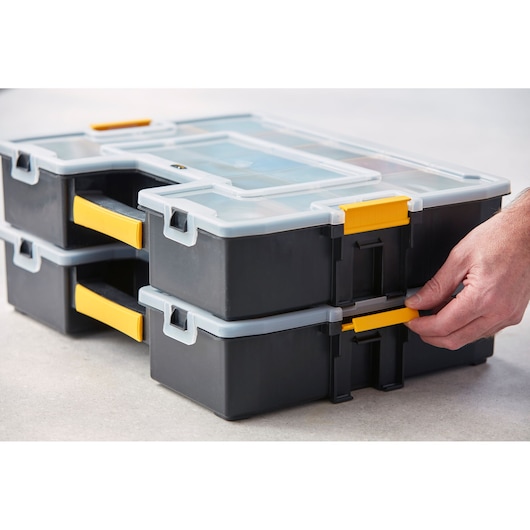 STANLEY 1-94-745 organiseurs empilables noir et jaune avec couvercles transparents, angle latéral rapproché, main ajustant le loquet.