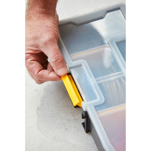 STANLEY 1-94-745 organiseur en gros plan, main ouvrant le loquet jaune sur le couvercle transparent.