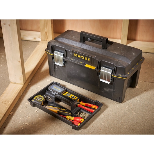 Boîte à outils STANLEY 1-94-749 avec plateau d’outils à main et vis sur sol d’atelier.