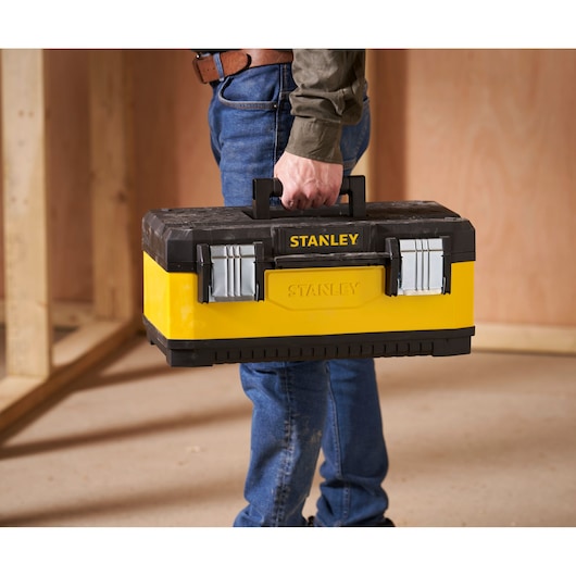 Boîte à outils STANLEY 1-95-612 jaune et noire tenue par une personne dans un environnement de chantier