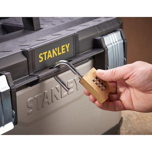 STANLEY 1-95-616 gereedschapskist met hand die een messing cijferslot opent, vooraanzicht.