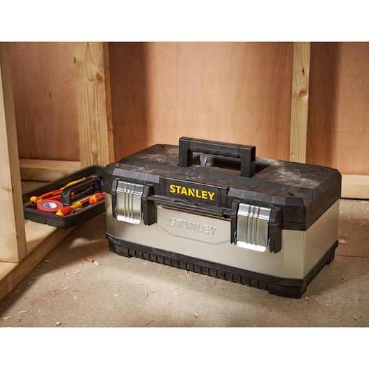 STANLEY 1-95-618 boîte à outils avec couvercle noir et fermetures métalliques sur le sol d’atelier, plateau d’outils à côté.