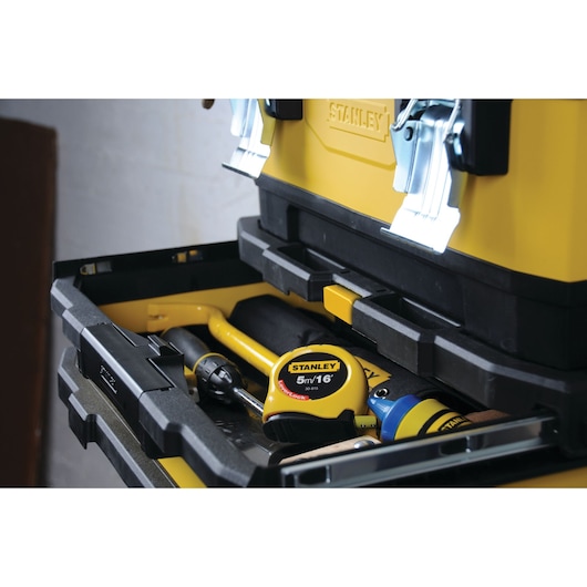 Boîte à outils STANLEY 1-95-621 avec tiroir ouvert montrant un mètre ruban et divers outils, vue en angle.