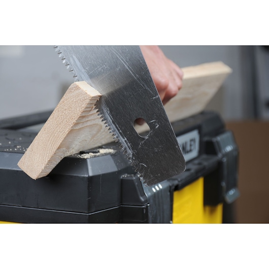 STANLEY 1-95-621 scie coupant une planche de bois sur une boîte à outils noire et jaune, photo en gros plan.