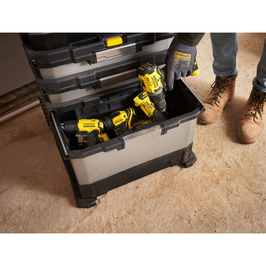 STANLEY 1-95-622 gereedschapskist met open lade, zichtbare elektrisch gereedschap en persoon met STANLEY handschoenen.