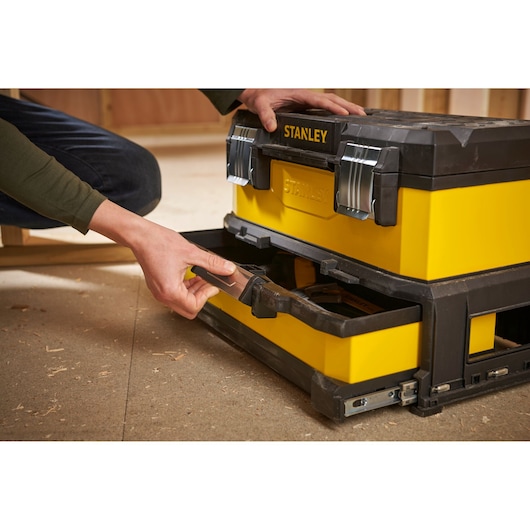 Stanley 1-95-829 gereedschapskist met lade open, geel en zwart, in een werkplaats.