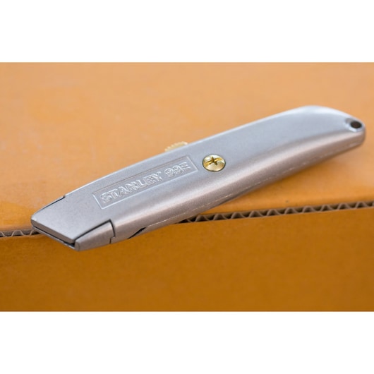 Couteau utilitaire argenté STANLEY 2-10-099 sur carton, vue latérale du produit.