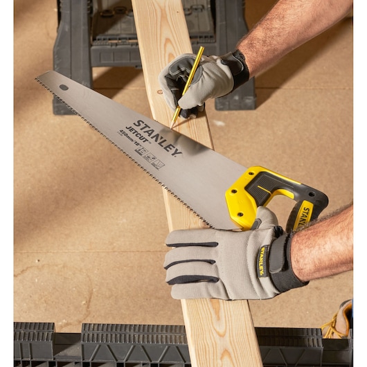 STANLEY 2-15-283 handzaag met gele handgreep, vastgehouden door gehandschoende hand, hout wordt gemarkeerd.
