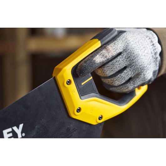 STANLEY 2-20-180 handzaag close-up, geel-zwart handvat met gehandschoende hand, fotografie.