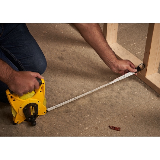 STANLEY 2-34-814 open rolmaat gebruikt op bouwvloer, geel huis, persoon meet houten frame.