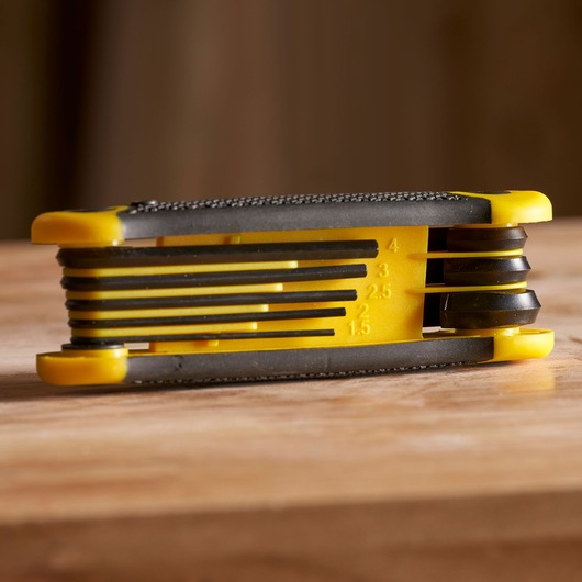 STANLEY 2-69-264 jeu de clés hexagonales pliantes jaune et noir, angle latéral sur une surface en bois.