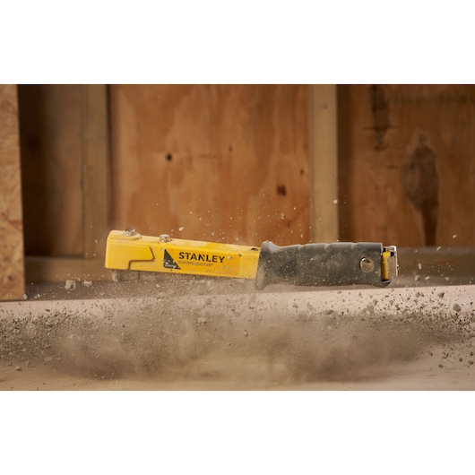 Foto van STANLEY 6-PHT150 heavy-duty tacker in actie, met stof op bouwplaats.