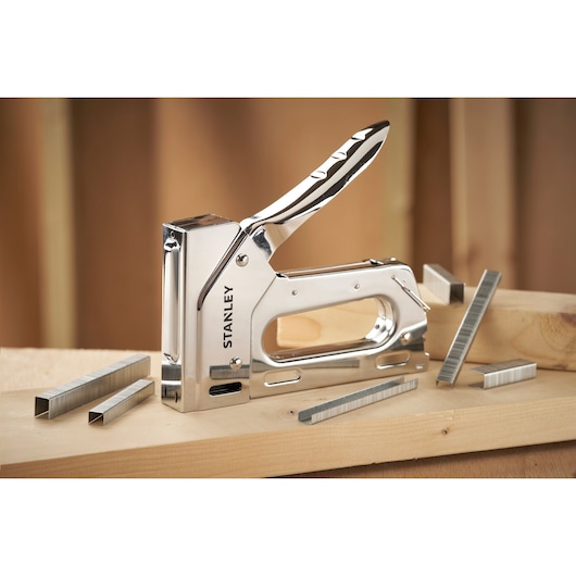 STANLEY 6-TR110 zware nietmachine met chromen afwerking en nietjes, schuin op houten planken.