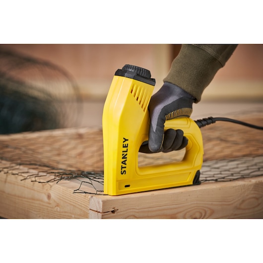 Stanley 6-TRE550 agrafeuse électrique jaune, vue latérale, utilisée sur bois et grillage.