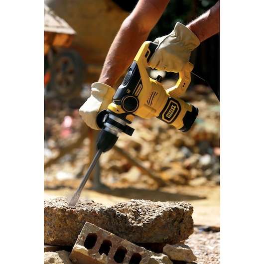 STANLEY FME1250K boorhamer in gebruik, geel-zwart ontwerp, boort in beton op bouwplaats.