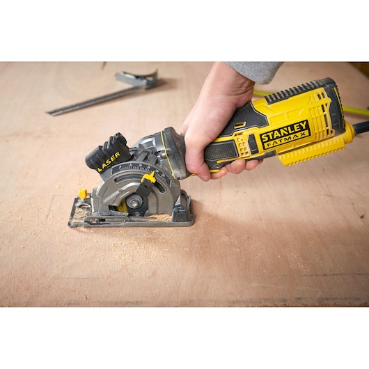 Photo de la scie circulaire portative STANLEY FME380K avec guide laser utilisée sur une surface en bois.
