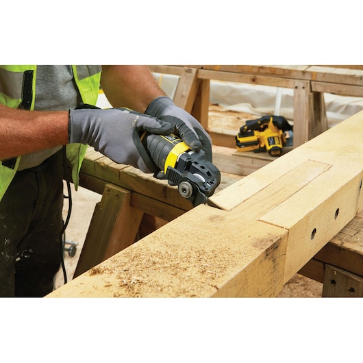 STANLEY FME650K multitool wordt gebruikt om hout te zagen op werkbank in werkplaats, close-up van gebruik.