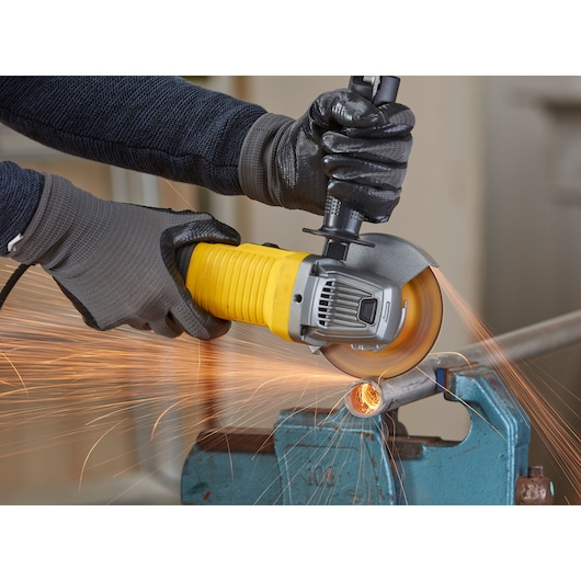 STANLEY FMEG210K haakse slijper in gebruik, snijdt metalen buis met vonken, close-up fotografie.