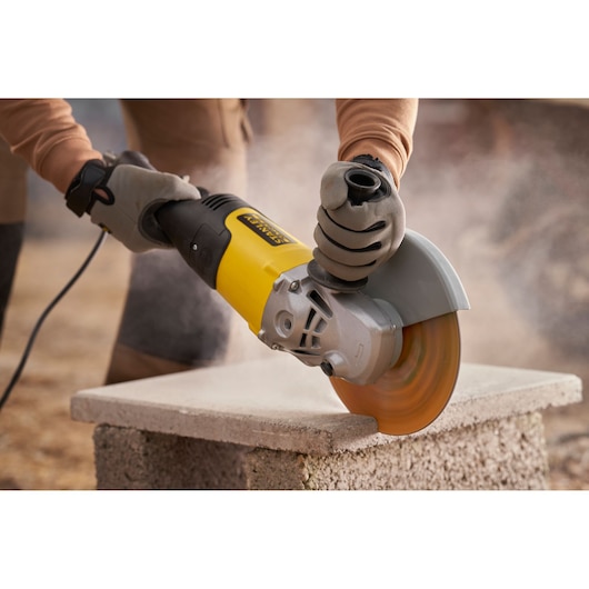 STANLEY FMEG232 meuleuse d’angle en utilisation pour couper un bloc de béton, vue rapprochée.