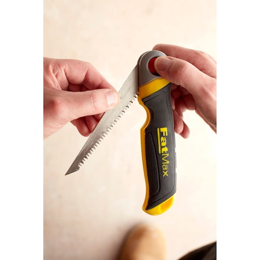 STANLEY FMHT0-20559 opvouwbare handzaag met zwart-gele FatMax handgreep, vastgehouden, close-up.