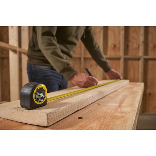 STANLEY FMHT0-33864 rolmaat op hout in werkplaats, persoon zet een maat af.