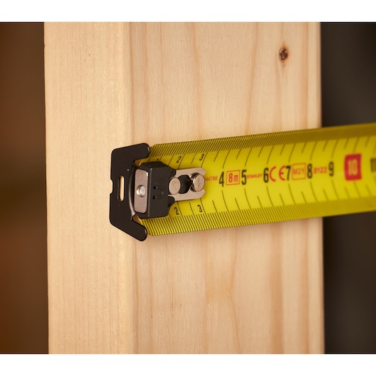 STANLEY FMHT0-33868 rolmaat met gele band meet houten plank, close-up zijaanzicht.