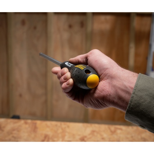 Photo d'une main tenant un tournevis STANLEY FMHT0-62623 avec manche ergonomique noir et jaune.