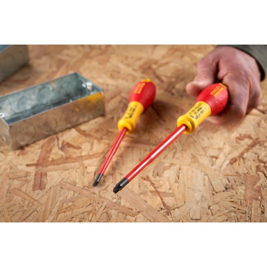 STANLEY FMHT0-62649 geïsoleerde schroevendraaier met rood-gele handgreep, getoond in gebruik op triplex oppervlak.