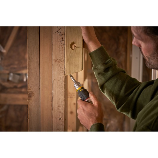 STANLEY FMHT0-62688 tournevis utilisé pour visser une vis dans un cadre en bois, vue rapprochée sur chantier.