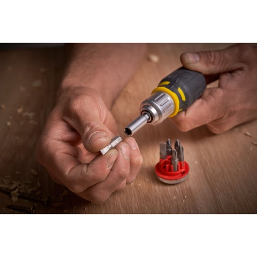STANLEY FMHT0-62688 set de tournevis avec embouts interchangeables, gros plan des mains changeant un embout sur une surface en bois.