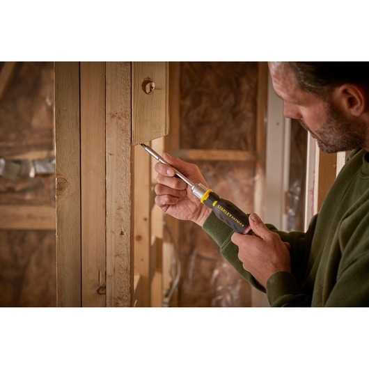 Foto van STANLEY FMHT0-62690 schroevendraaier gebruikt op houten constructie door persoon met groene trui.