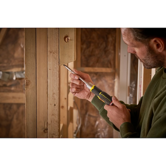 Photo du tournevis STANLEY FMHT0-62691 utilisé sur un cadre en bois dans un chantier.
