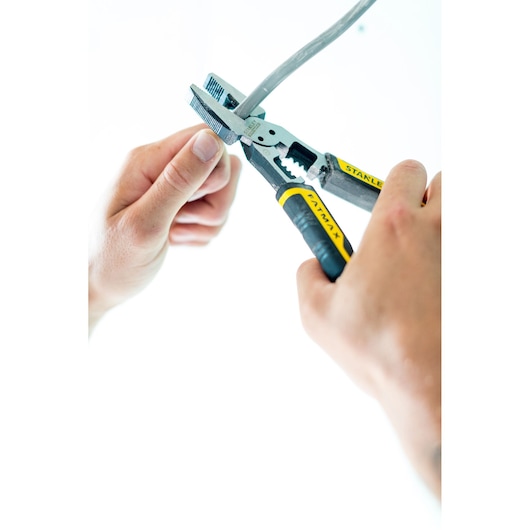 STANLEY FMHT0-75469 tang met zwart-gele handgrepen die kabel knipt, close-up met handen, productfotografie.