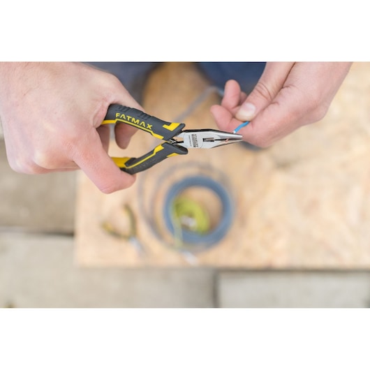 Pince à bec long STANLEY FMHT0-80517 avec poignée jaune-noir utilisée pour saisir un fil bleu.