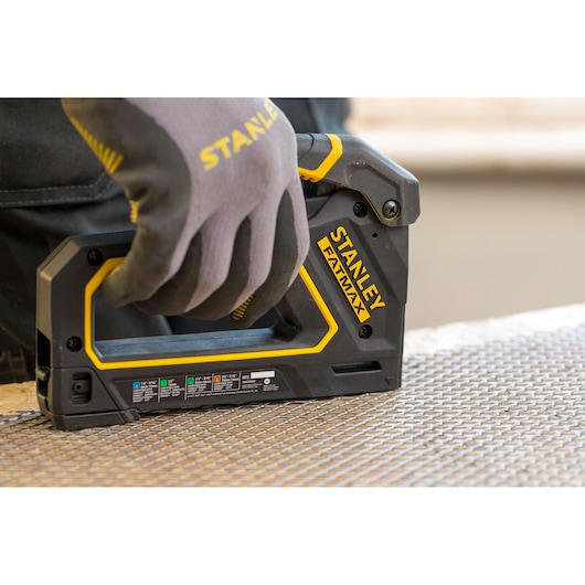 Photo de l'agrafeuse STANLEY FMHT0-80550 FATMAX en utilisation sur une surface en treillis métallique.