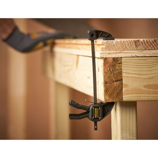 STANLEY FMHT0-83231 photographie d’un serre-joint à barre fixant le bord d’un établi en bois