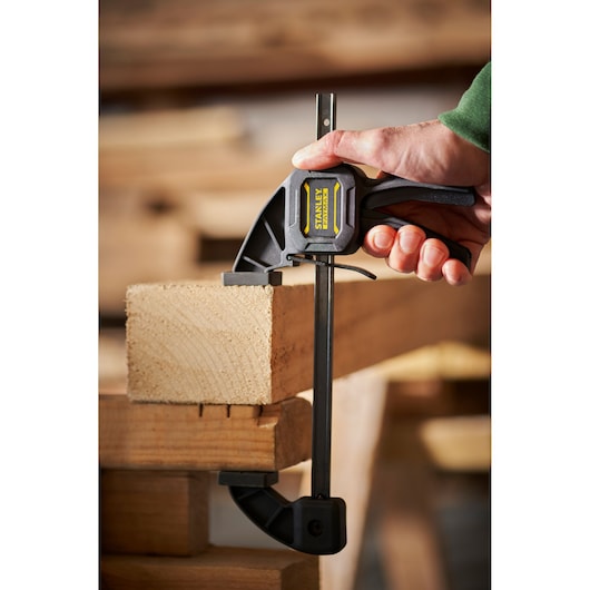 STANLEY FMHT0-83232 photographie de serre-joint rapide fixant une planche de bois dans un atelier.