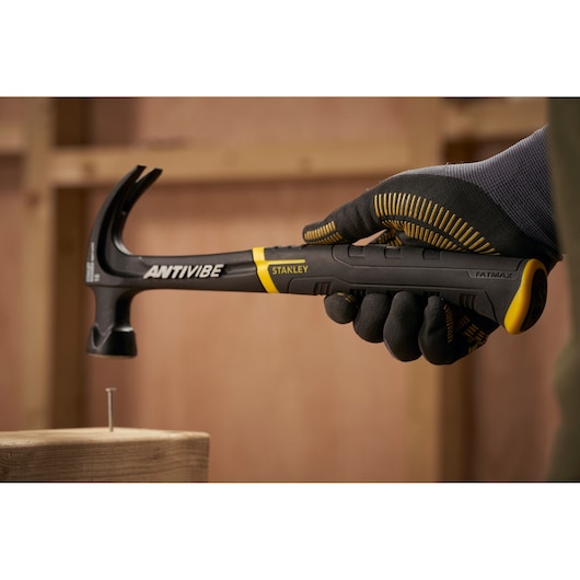 STANLEY FMHT1-51275 klauwhamer met zwart-geel handvat, vastgehouden door een gehandschoende hand, FATMAX ANTIVIBE serie.