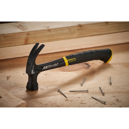 STANLEY FMHT1-51275 klauwhamer met zwart-gele handgreep op houten oppervlak met verspreide spijkers.