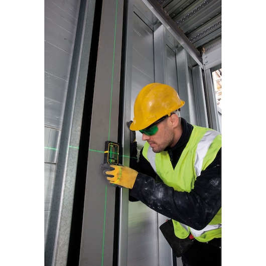 STANLEY FMHT1-74267 laserwaterpas in gebruik op metalen frame door werknemer met gele helm en vest, bouwplaats.