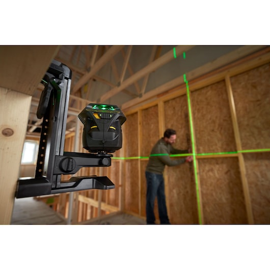 STANLEY FMHT1-77356 laserwaterpas projecteert groene lijnen op muur in bouwplaats, zijaanzicht.