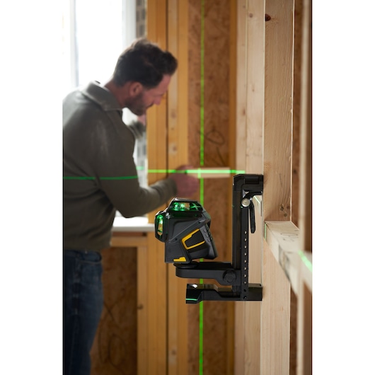 STANLEY FMHT1-77356 groene straal laserwaterpas aan de muur gemonteerd in bouwomgeving, man op achtergrond.