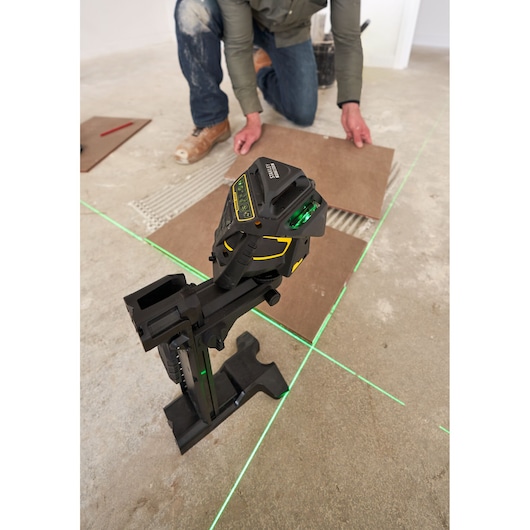 STANLEY FMHT1-77356 laserwaterpas projecteert groene lijnen op de vloer, gebruikt voor tegeluitlijning tijdens installatie.