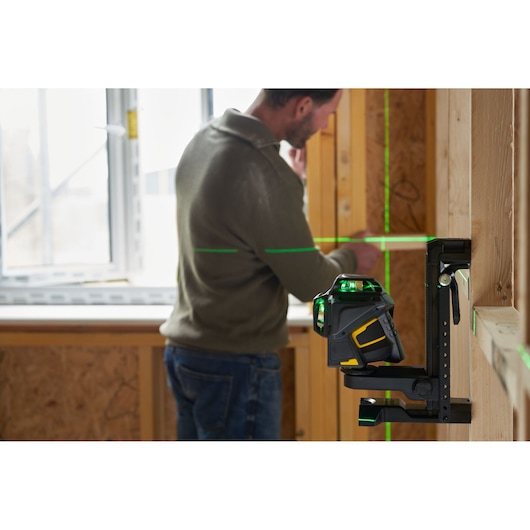 STANLEY FMHT1-77356 kruislijnlaser op beugel die groene lijnen projecteert in een houten constructie.