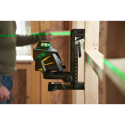 STANLEY FMHT1-77356 laserwaterpas projecteert groene lijnen in een bouwomgeving, gemonteerd op een verticale steun.